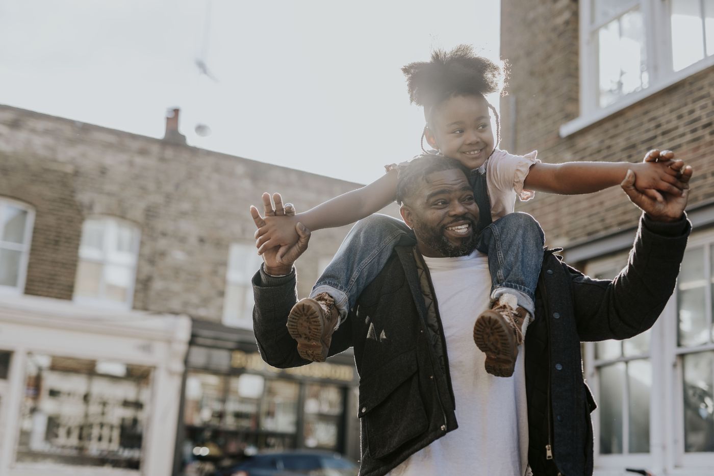 Father carrying his daughter on his shoulders outside their East London home